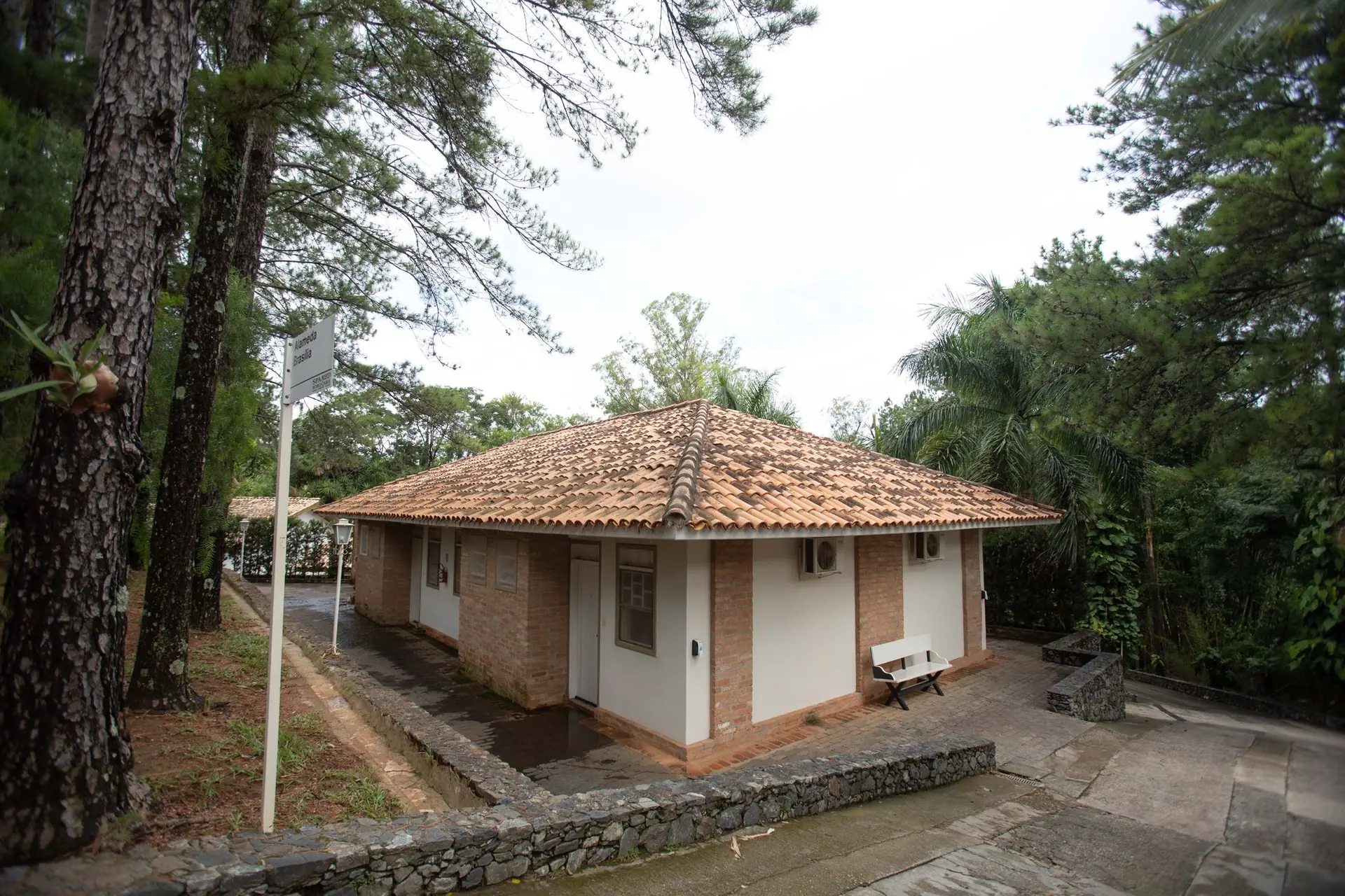 Fachada da Colonial Mineira do Spa Med, em tijolo e branco, com telhado de telha e banco na entrada
