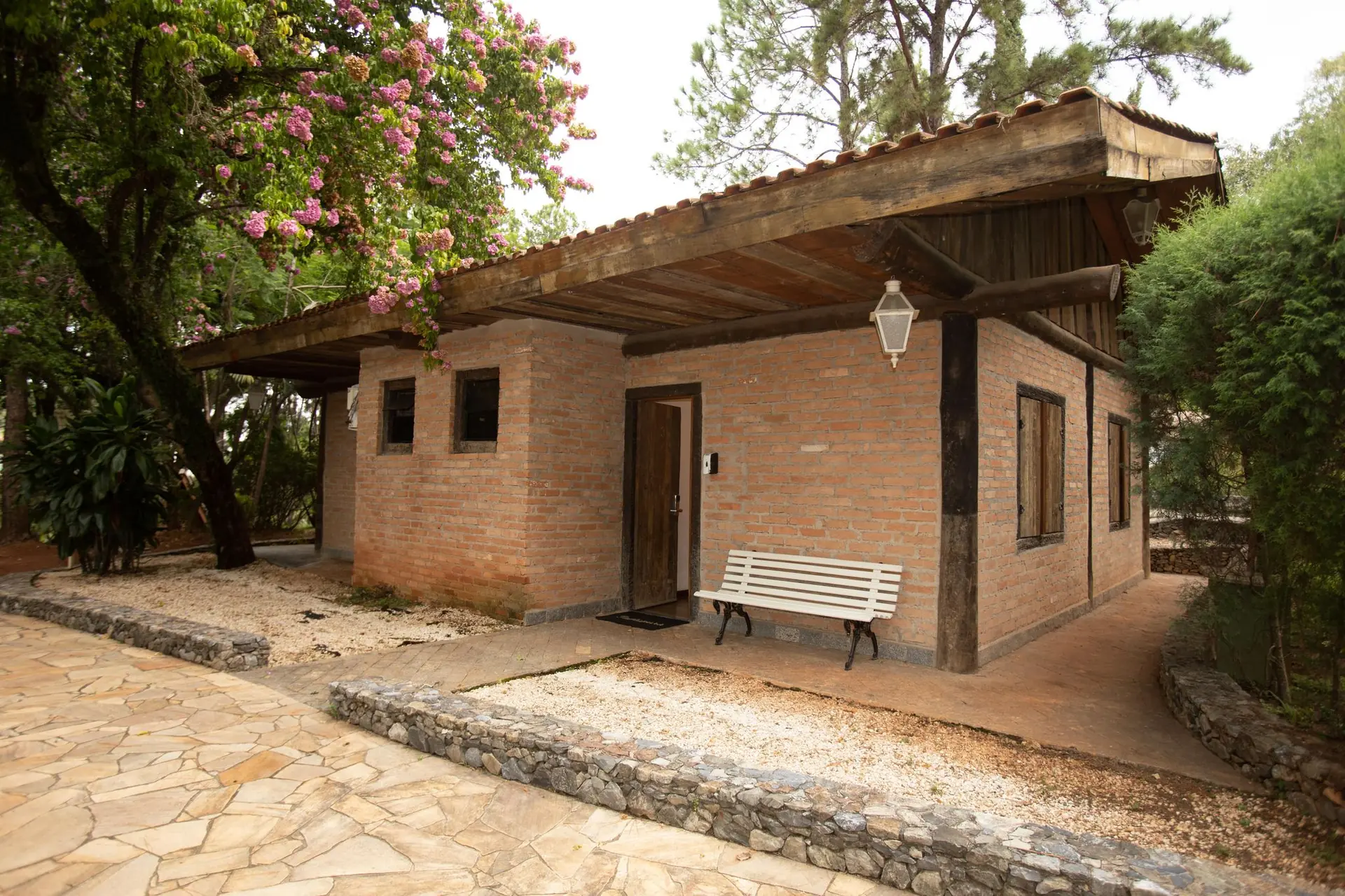 Fachada da Colonial Pantaneira do Spa Med, em tijolo aparente, com pergolado de madeira e banco na entrada