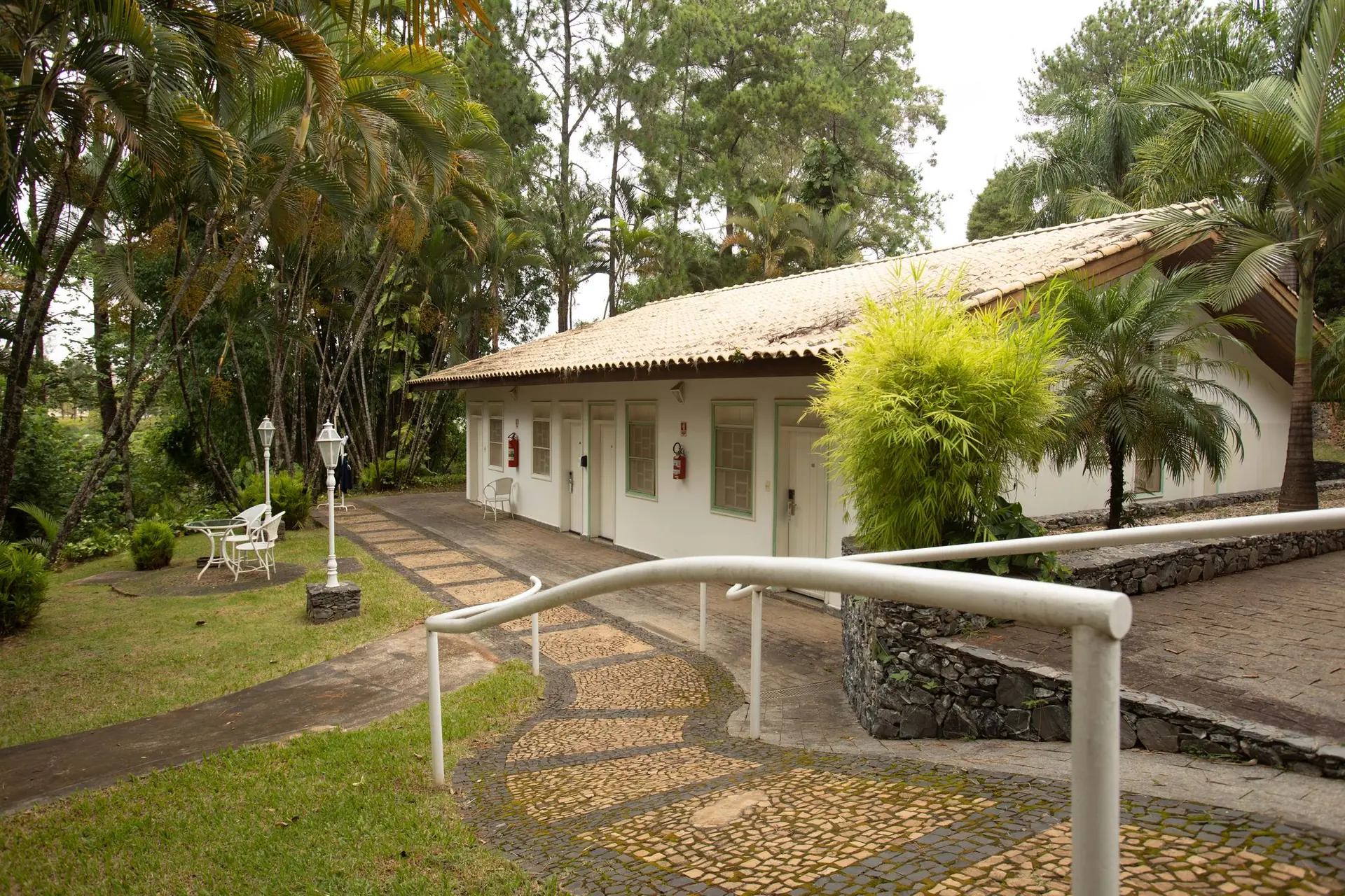 Fachada da Colonial Paulista do Spa Med, branca com esquadrias verdes, entre palmeiras