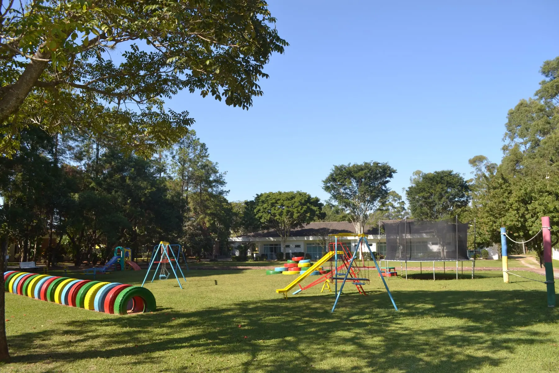 Gramado central do Spa Med com o circuito de brinquedos coloridos e o playground ao fundo