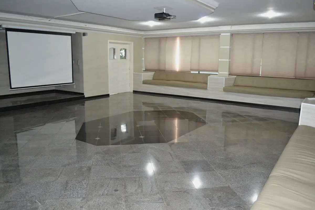 Sala do business center com piso espelhado, tela de projeção e cadeiras na lateral