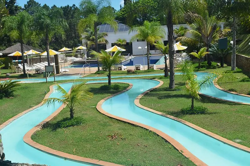 Caminho das Águas visto do alto, com o percurso turquesa serpenteando entre gramado e palmeiras