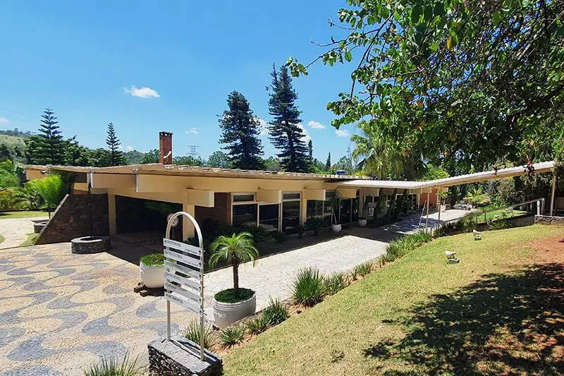 Casa sede do Spa Med, de laje baixa e pedra, vista do gramado em declive