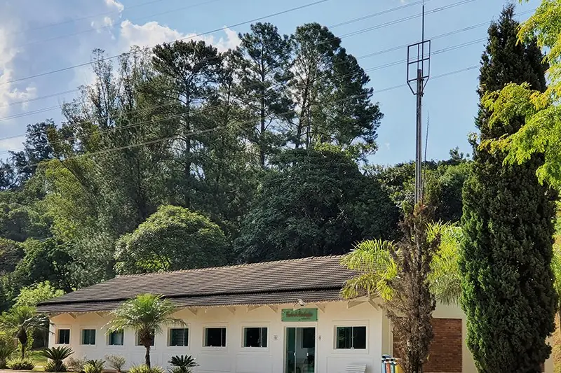 Fachada do centro de fisioterapia entre os ciprestes, com o caminho de acesso à frente
