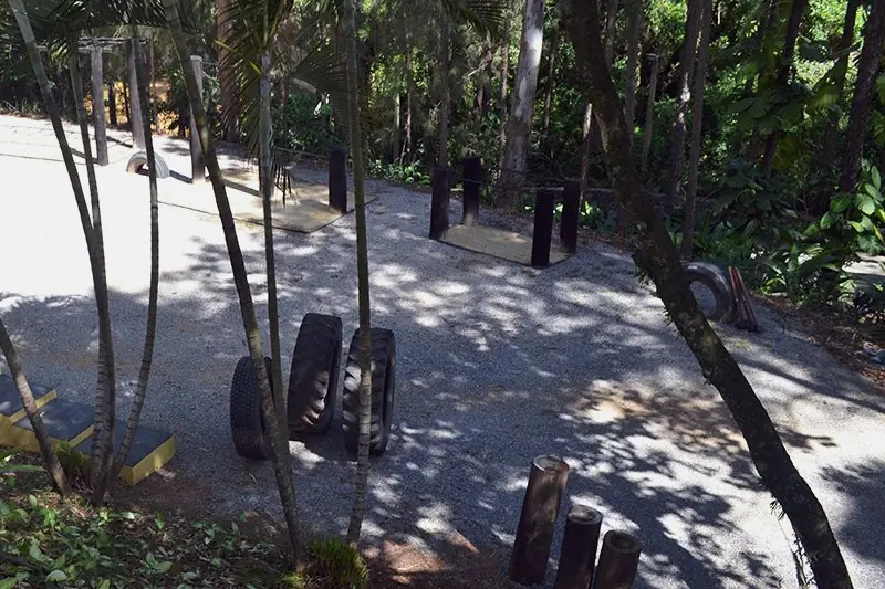 Área de treino funcional ao ar livre, com sacos de peso pendurados sob as árvores