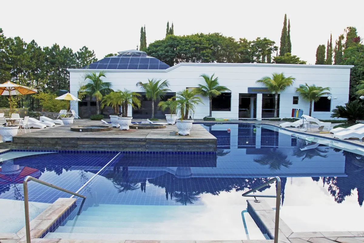 Piscina do centro de hidroterapia vista do deck, com o bloco de janelas azuis atrás