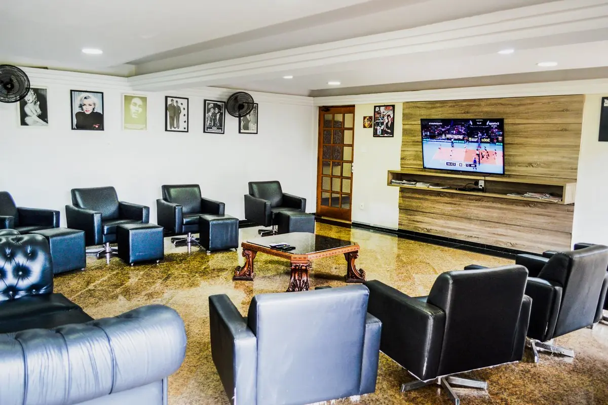 Sala de home theater com poltronas de couro, televisão na parede de madeira e retratos emoldurados