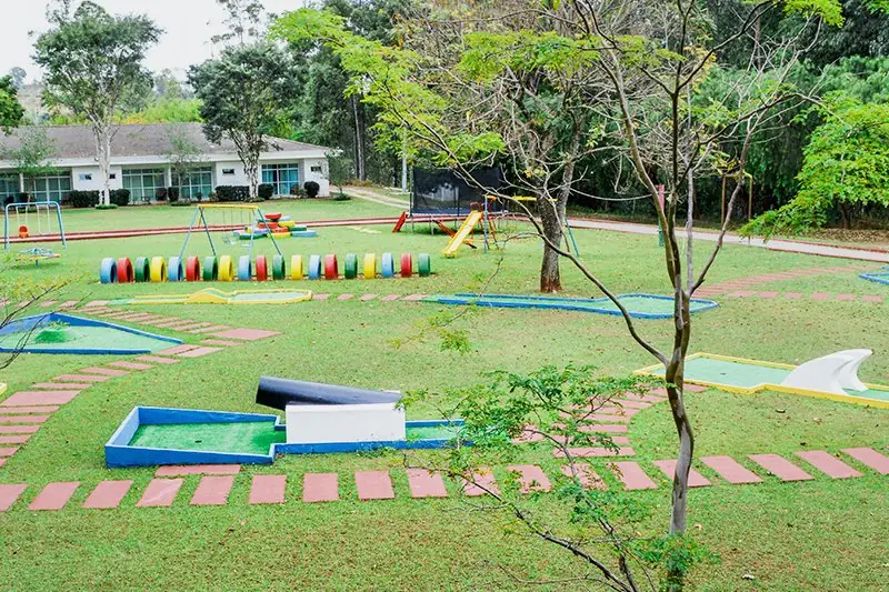 Vista ampla do mini golfe, com as pistas verdes e os obstáculos espalhados pelo gramado