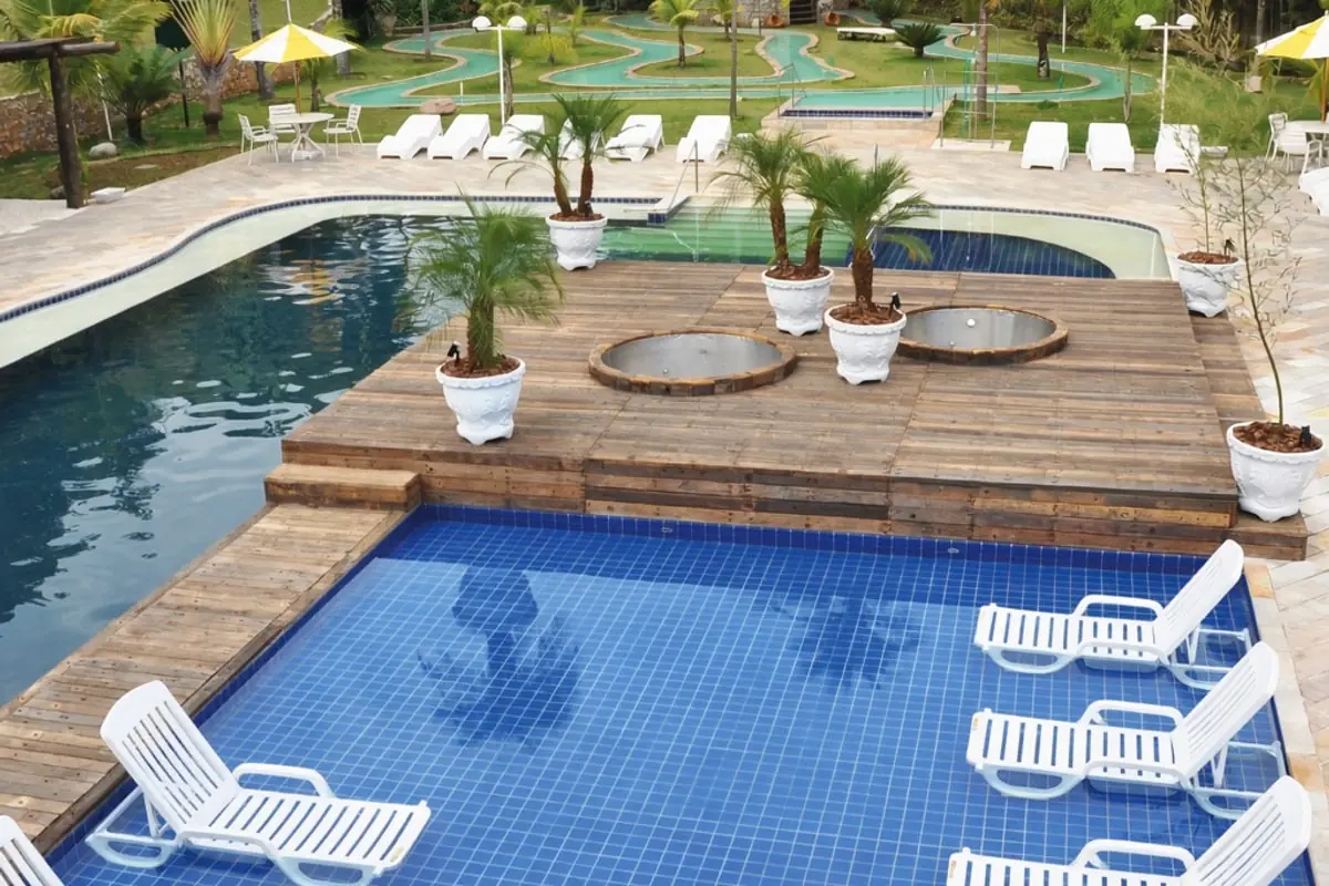 Deck de madeira sobre a piscina azul, com espreguiçadeiras brancas