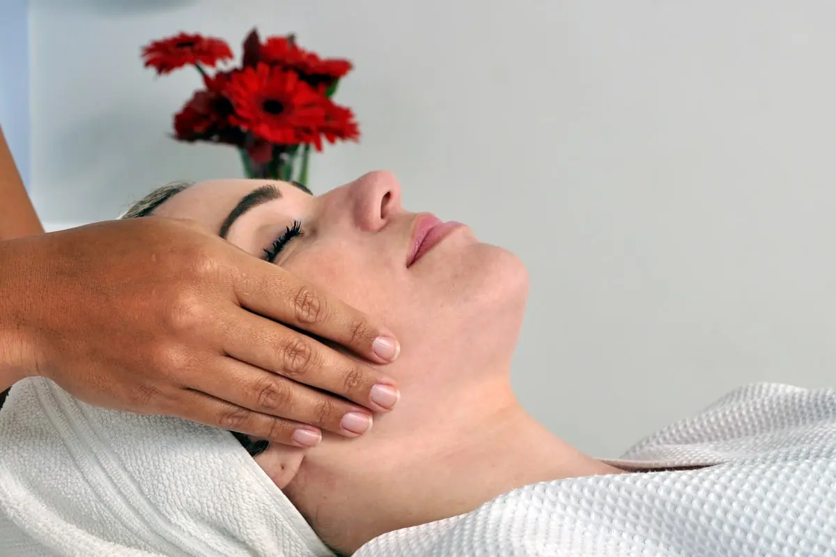 Tratamento facial em andamento, com a hóspede deitada e flores ao lado