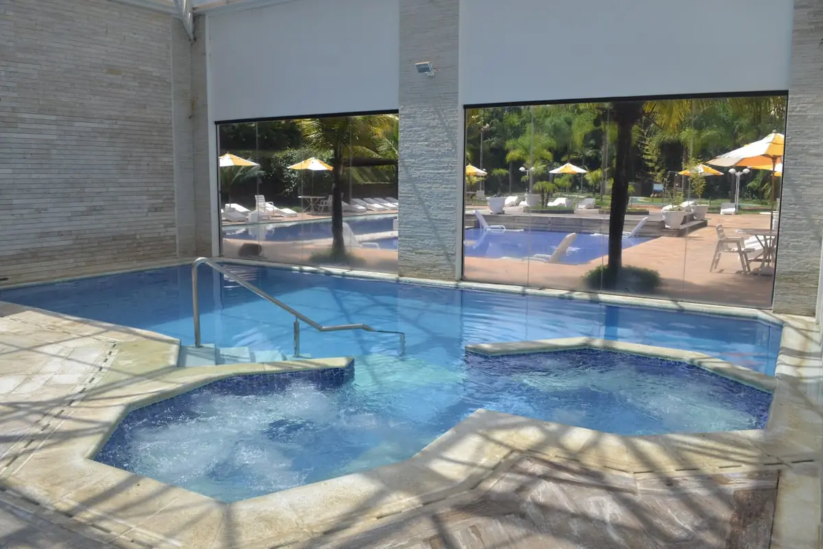 Piscina de hidromassagem coberta, com a parede de vidro aberta para a piscina externa