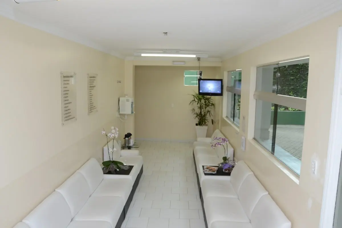 Sala de espera do centro médico, com sofás brancos e orquídeas