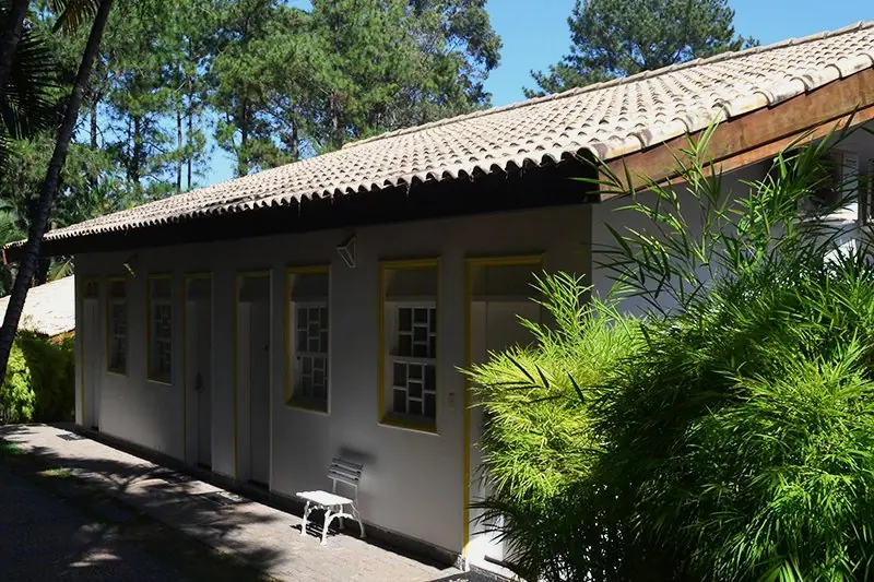 Bloco Colonial Paulista de telhado baixo e parede branca, com o bambuzal ao lado
