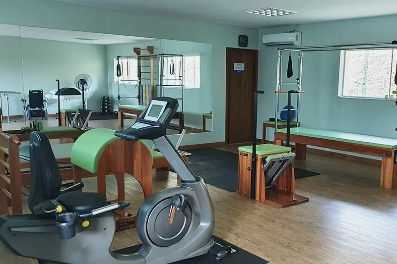 Praticante deitada no solo trabalhando com o aparelho de pilates e a bola suíça