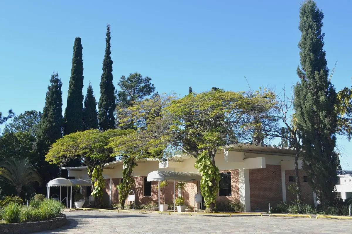 Fachada da recepção do Spa Med ao fim do estacionamento, entre ciprestes altos