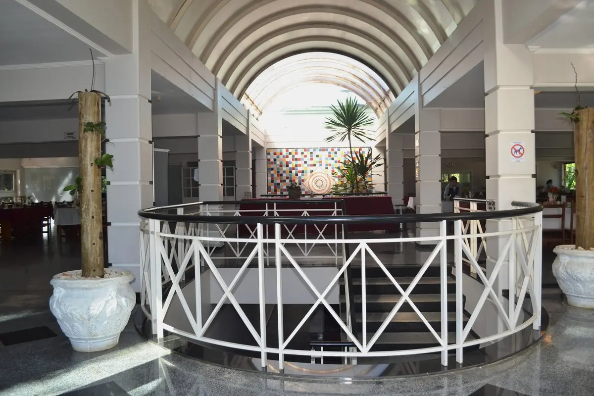 Hall de entrada do restaurante, com pé-direito em abóbada, balcão curvo e vasos de cerâmica