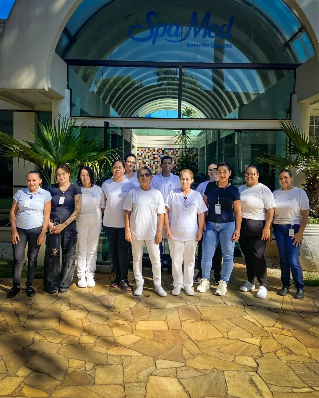 Parte da equipe do Spa Med reunida em frente à recepção, de uniforme branco e azul